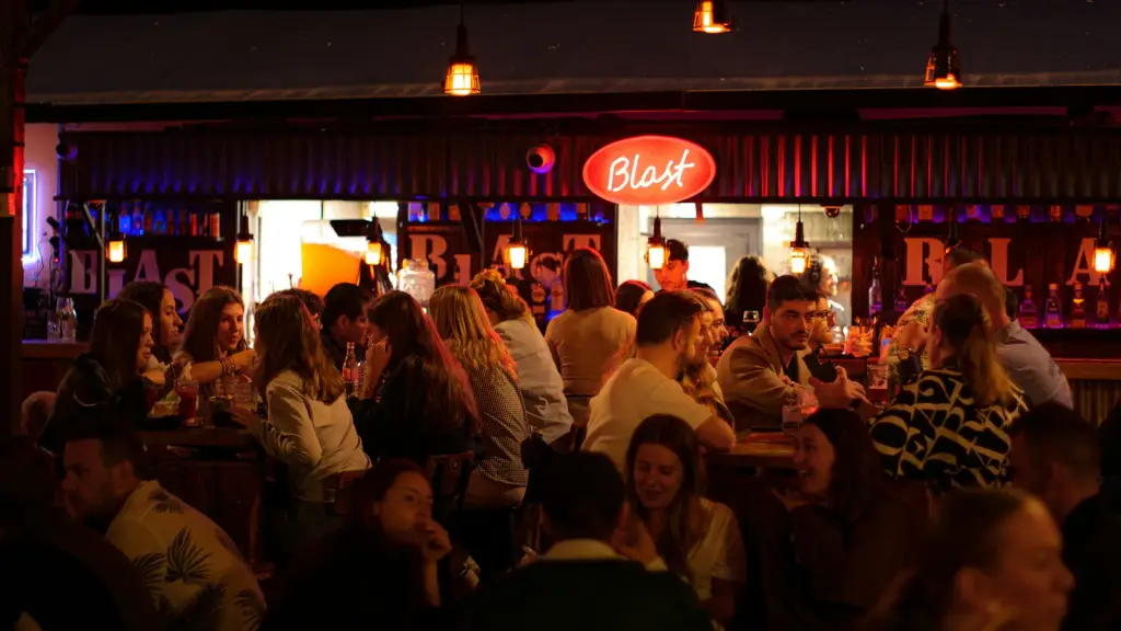 Customers filling a bar beneath a neon sign
