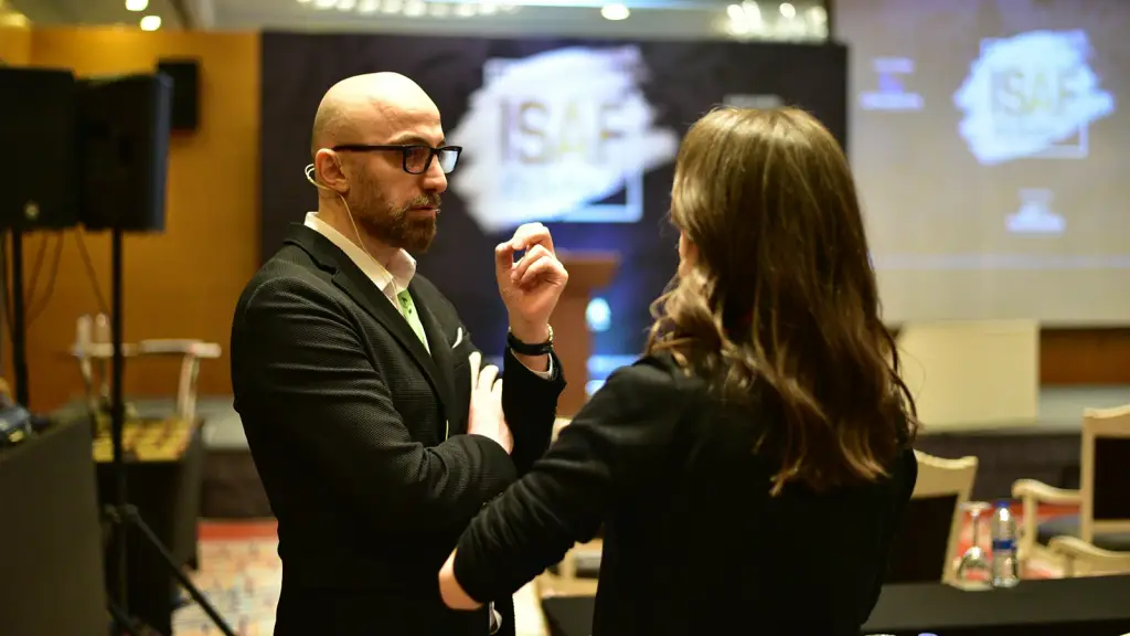 Two colleagues talking in front of a presentation screen at an event