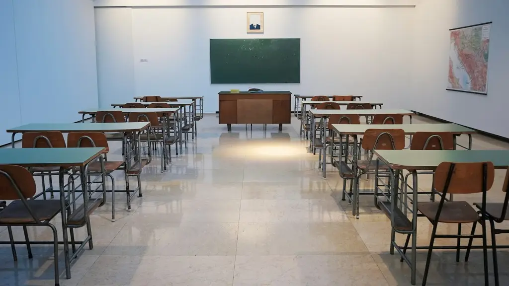 An empty classroom with desks facing a blackboard