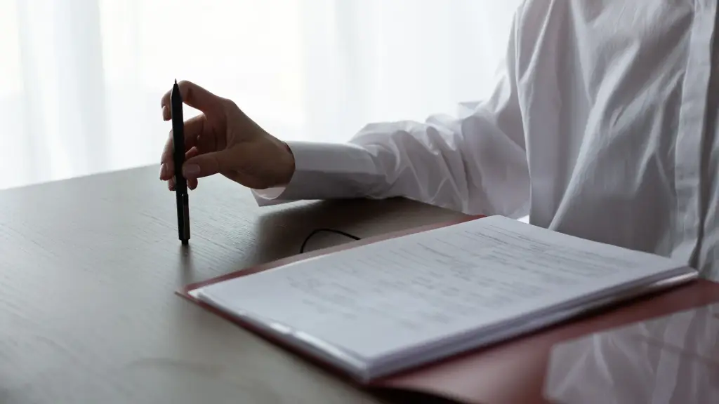 A person writing in a ring binder at a desk