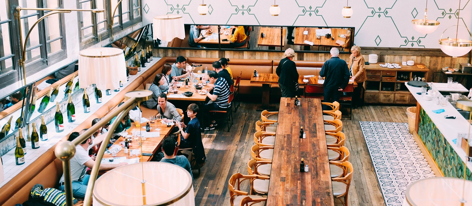 Diners at long communal tables in a busy restaurant